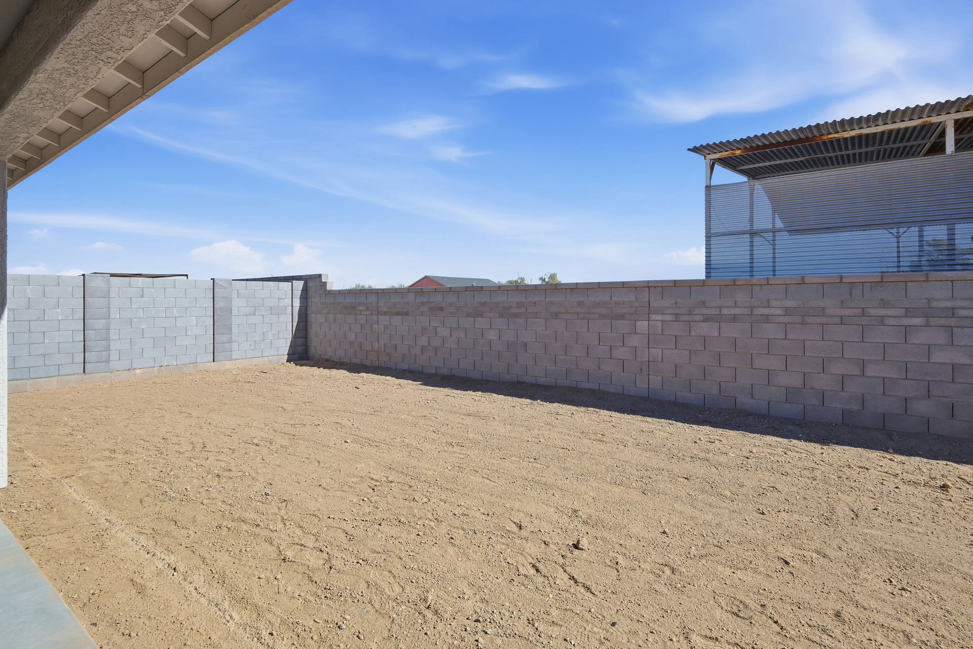 spacious dirt backyard with a concrete block wall