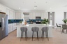 open-concept kitchen with grey barstools, white countertops, and stainless-steel appliances