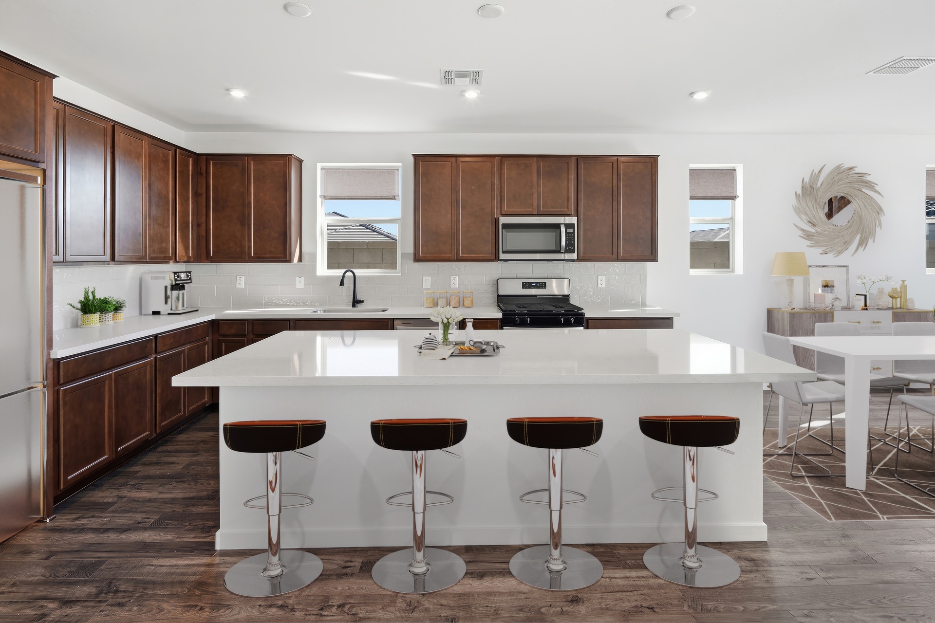 spacious kitchen with brown barstools, brown cabinets, and quartz countertops