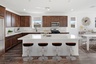 spacious kitchen with brown barstools, brown cabinets, and quartz countertops