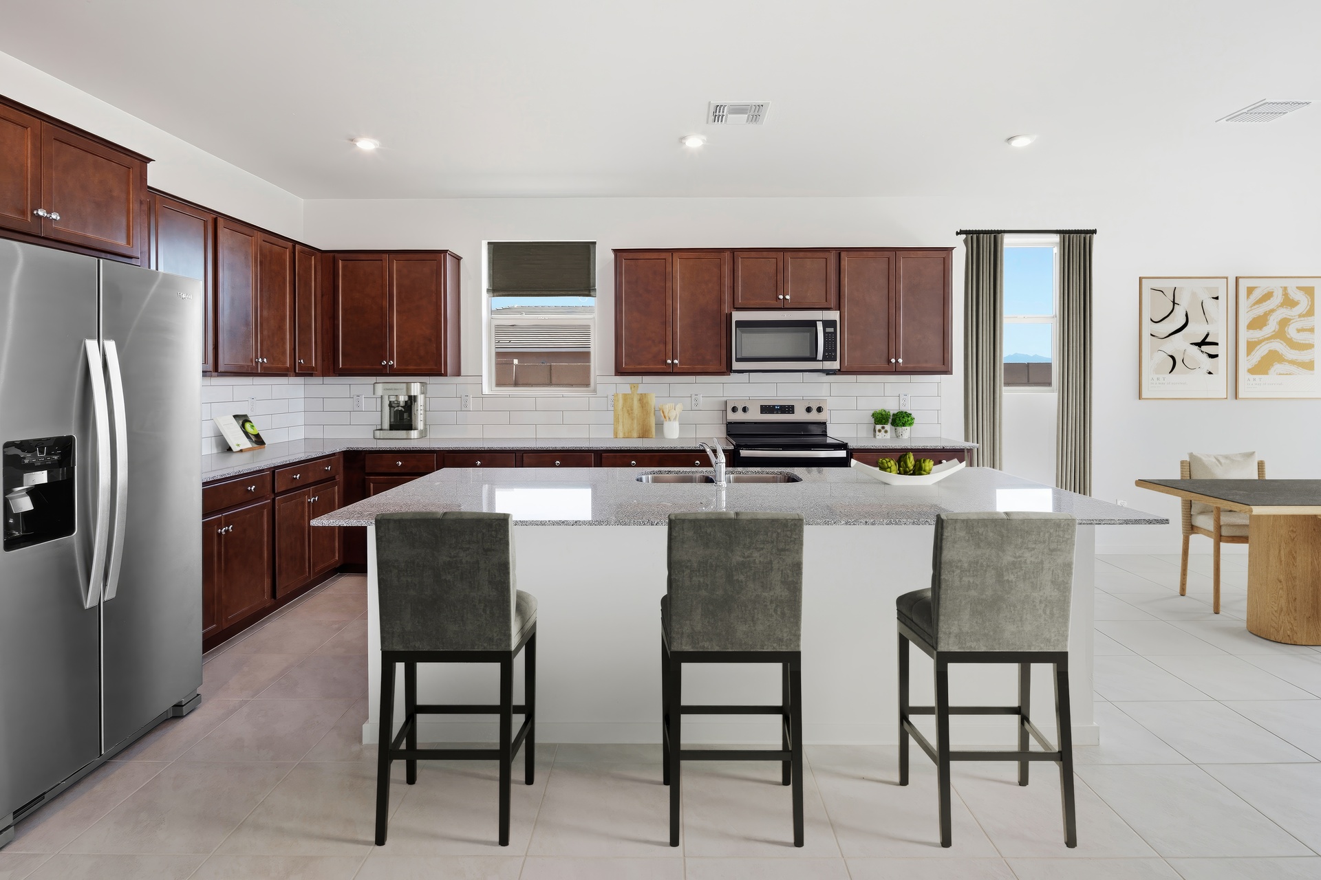 spacious kitchen with brown cabinets, quartz countertops, and grey barstools