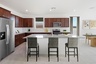 spacious kitchen with brown cabinets, quartz countertops, and grey barstools