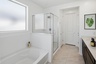 spacious bedroom with a walk-in shower, soaking tub, and brown cabinets
