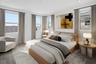spacious bedroom with a king-sized bed, plenty of natural light, and a white accent chair