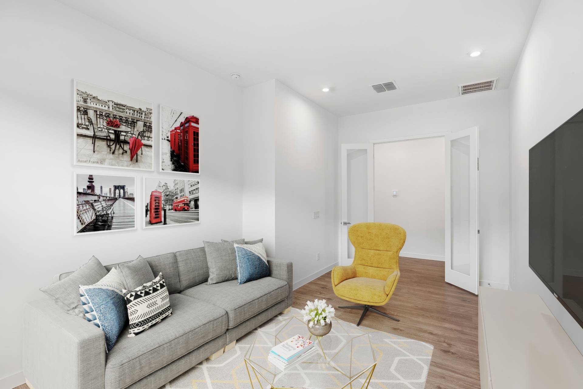 study being used as a secondary entertainment space with a large light grey couch, and a yellow accent chair