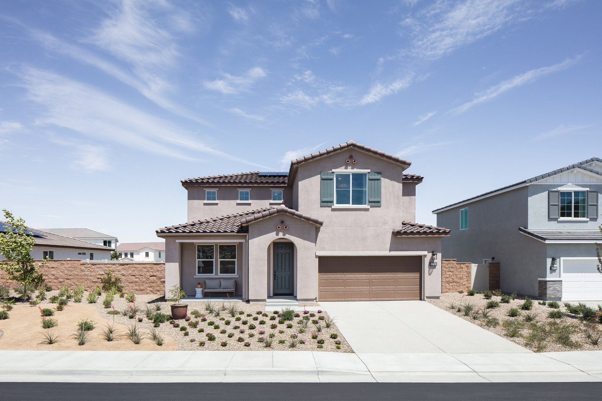 exterior of two-story home with brown garage and desert landscaping