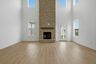 great room with two-story stone fireplace, wood floors, and large windows