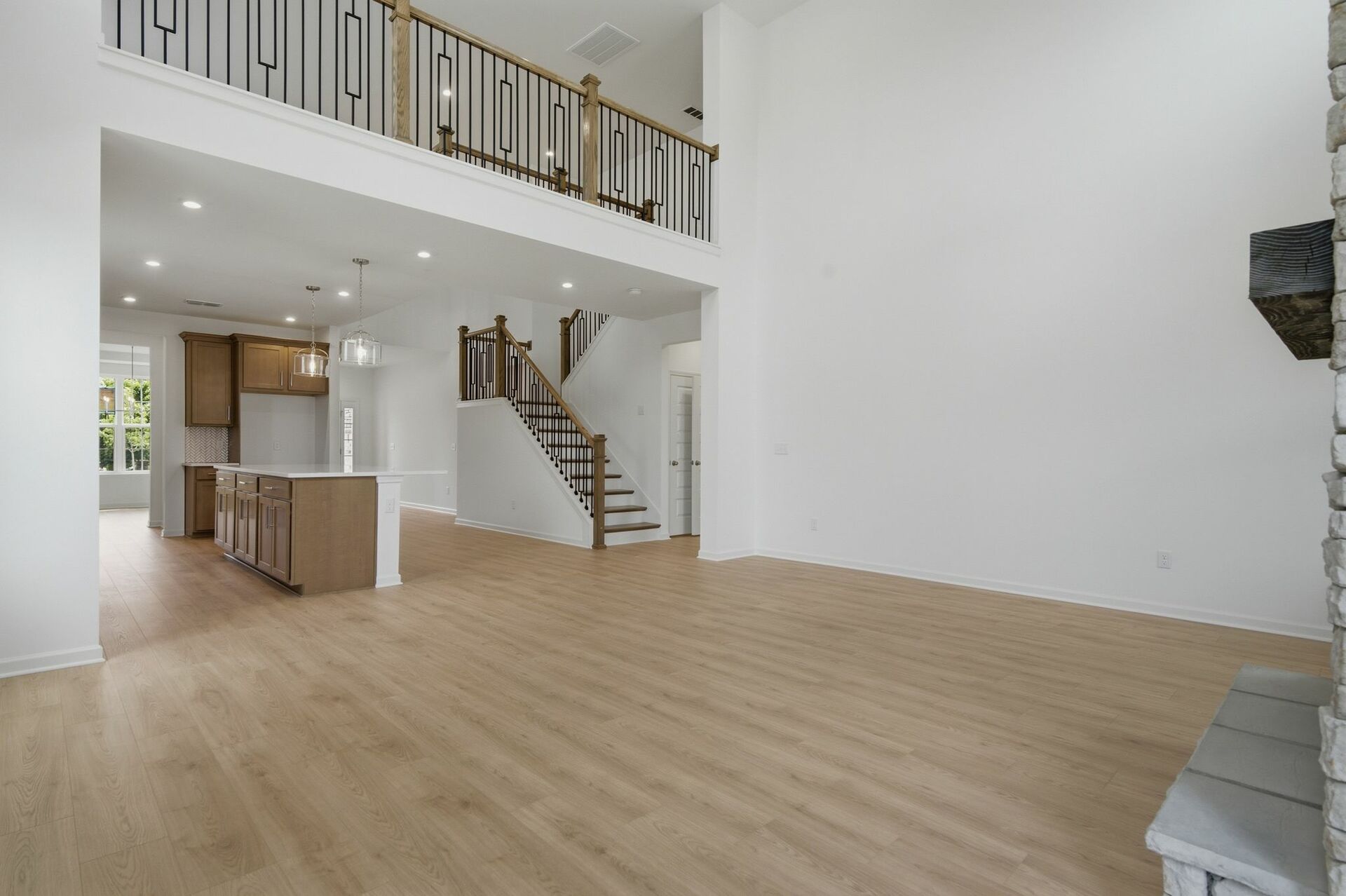 great room with two-story stone fireplace, wood floors, and large windows