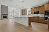kitchen with wood cabinets, white countertops, large island with accent lighting, built in microwave and oven, and stainless steel appliances