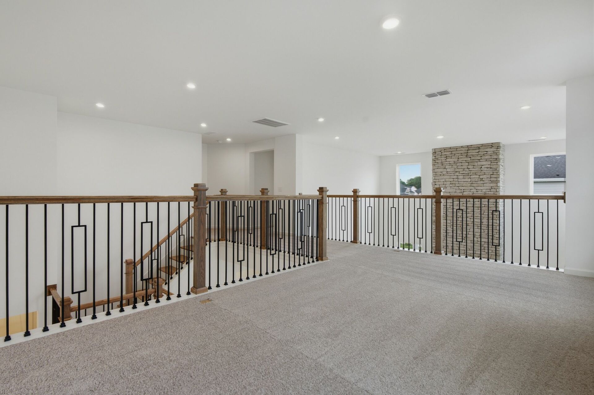 Loft with oak tread and iron railing, carpet, and large windows