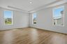 primary bedroom with wood floors, large windows, white walls, and tray ceiling