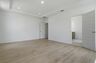 primary bedroom with wood floors, large windows, white walls, and tray ceiling