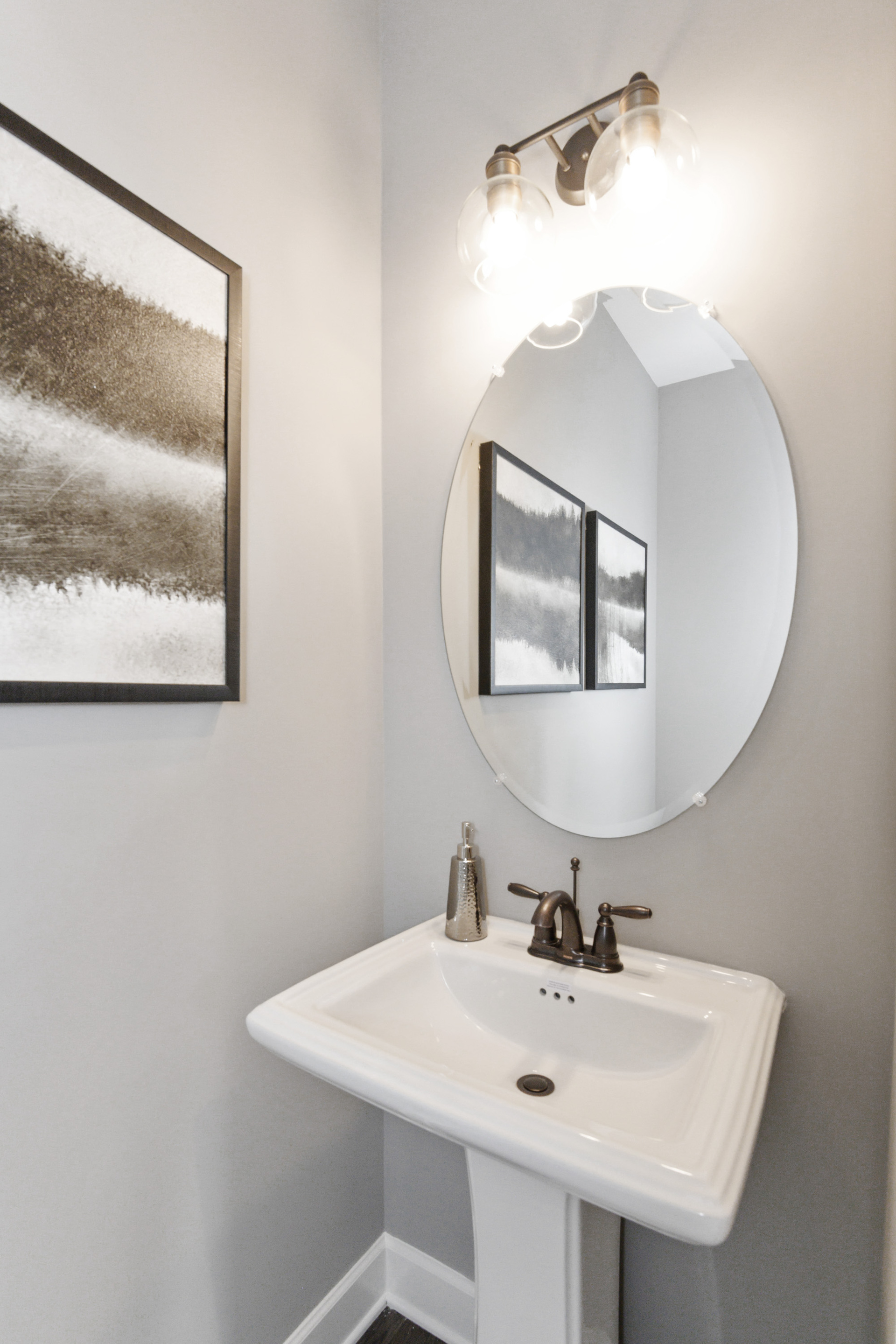 powder room with oval mirror and single standing sink