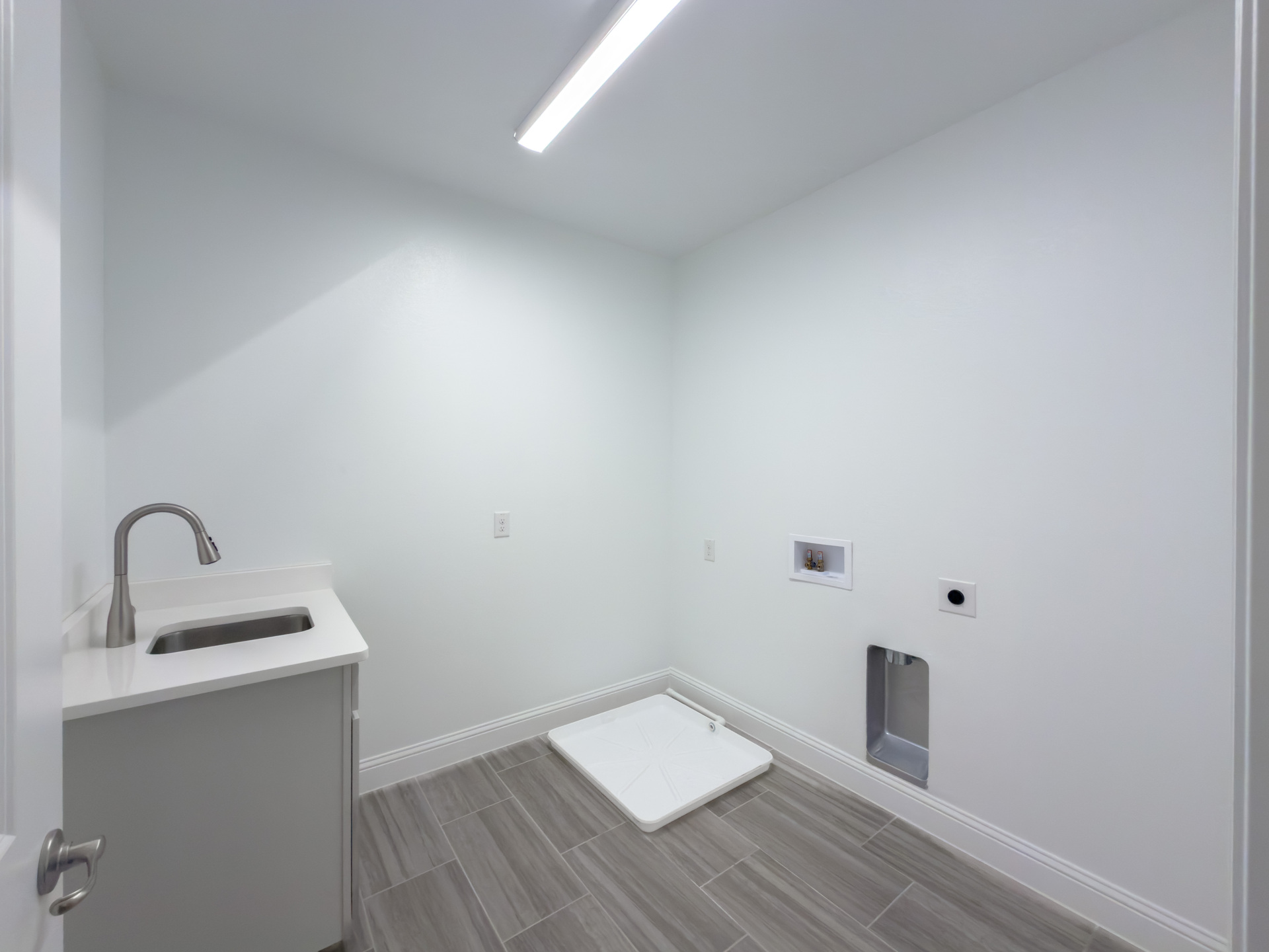 spacious laundry room with tile flooring and sink