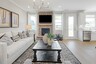 great room with wood flooring, white sofa, large area rug, stone fireplace, and large windows