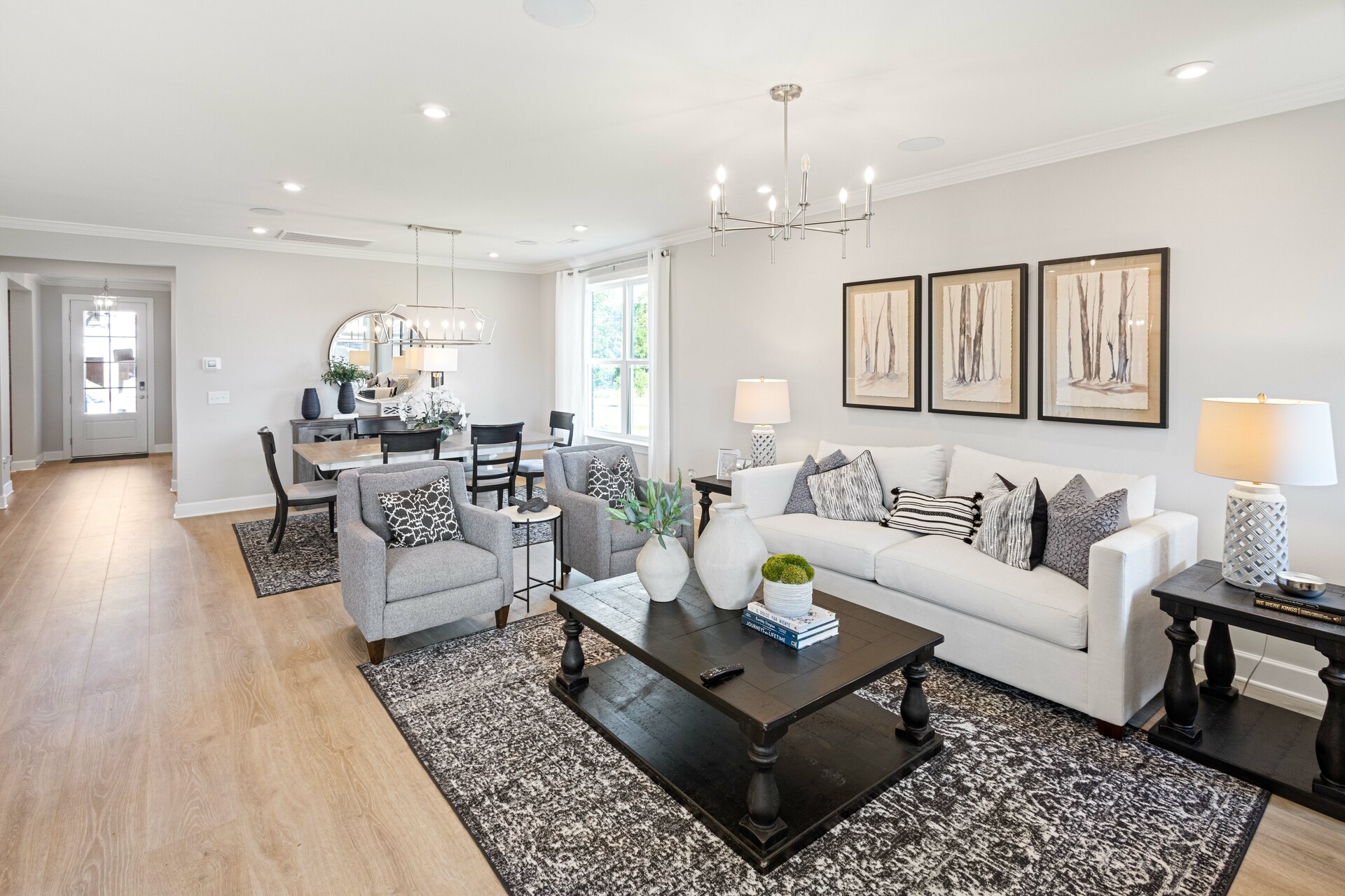 great room with wood flooring, white sofa, large area rug, stone fireplace, and large windows