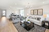 great room with wood flooring, white sofa, large area rug, stone fireplace, and large windows