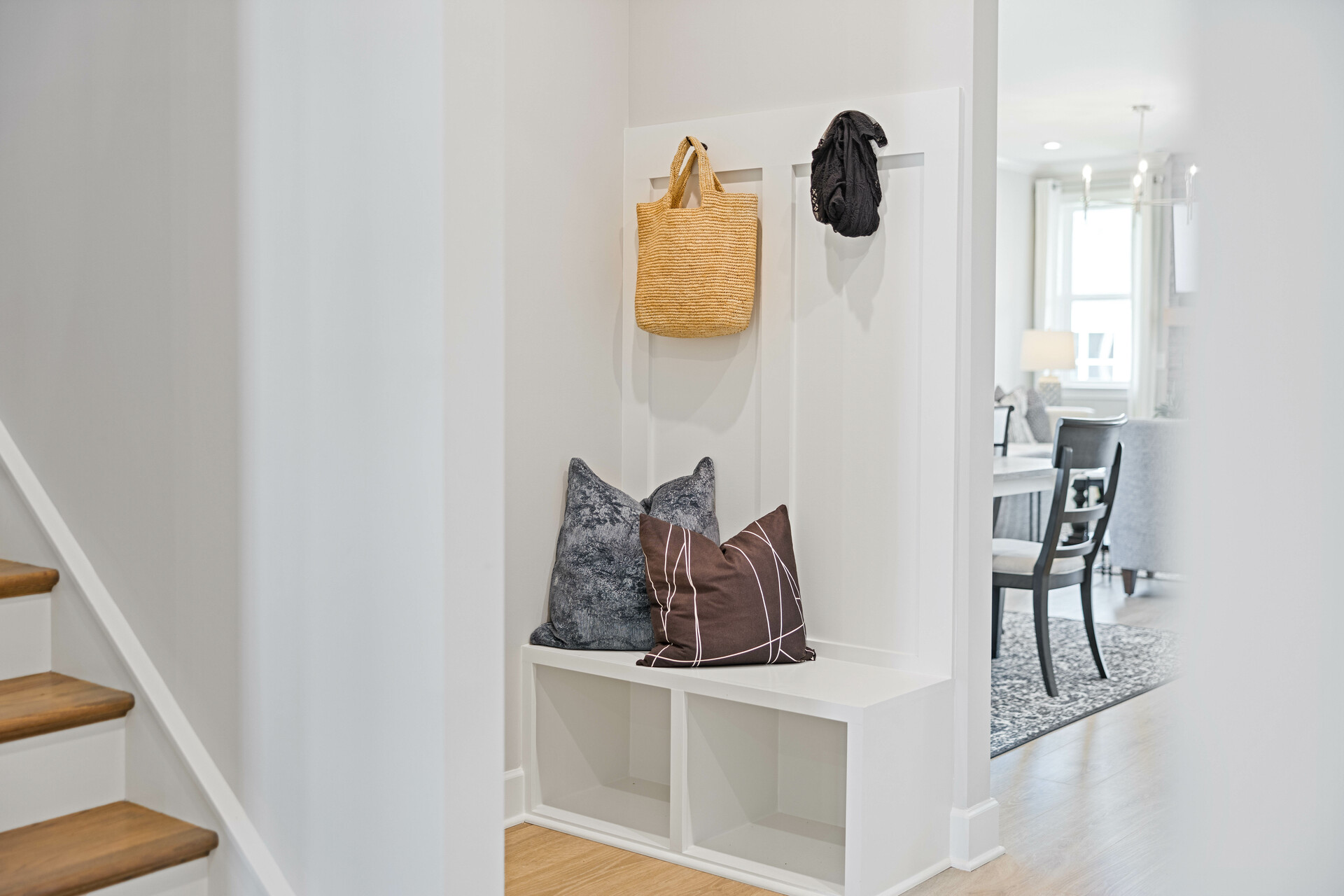 mud room with a view of the dining room, white valet bench, and hooks on the wall