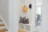 mud room with a view of the dining room, white valet bench, and hooks on the wall