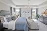 primary bedroom with carpet flooring, large bed, nightstands, large windows and a tray ceiling