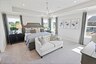 primary bedroom with carpet flooring, large bed, nightstands, large windows and a tray ceiling