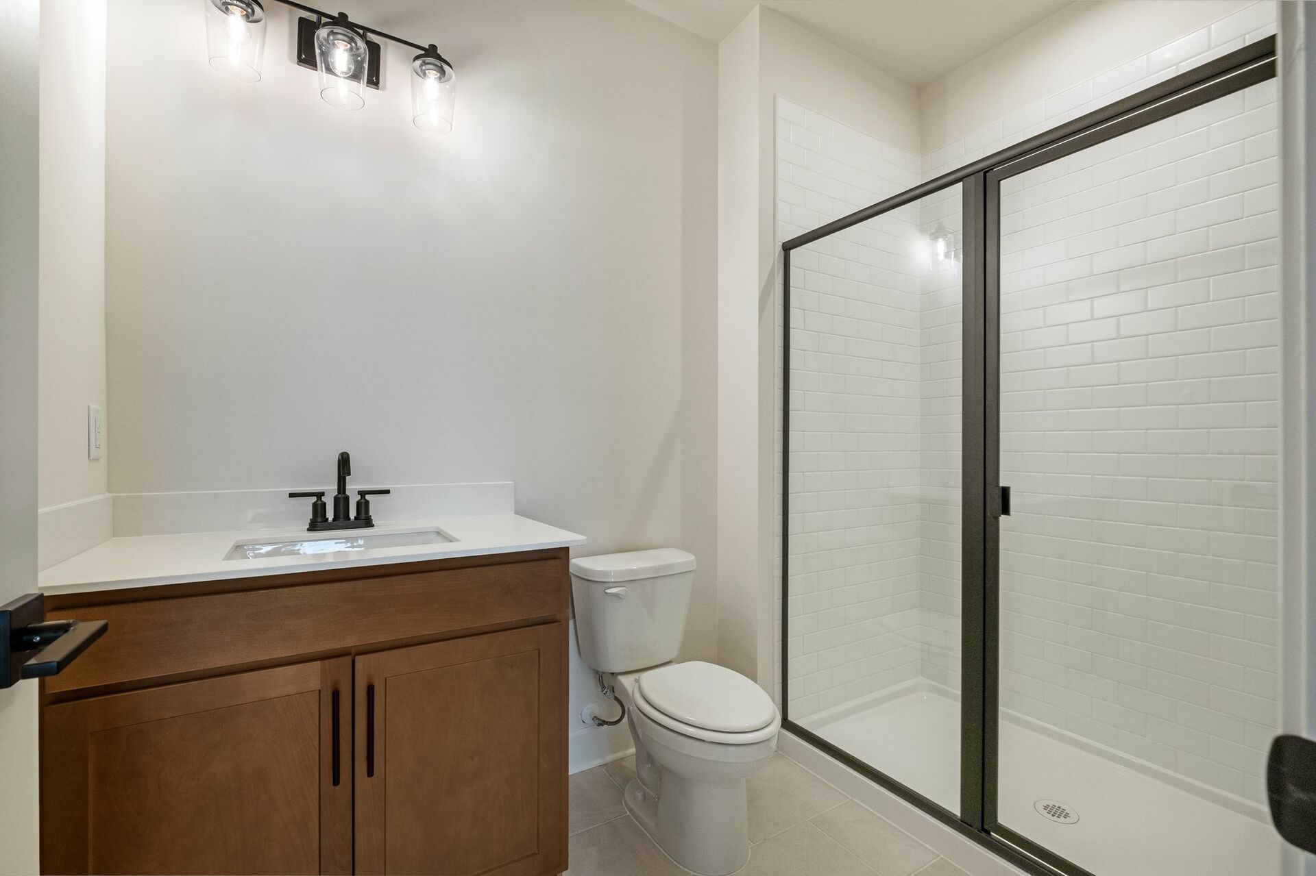 secondary bathroom with wood cabinets, white countertops, and a walk-in shower
