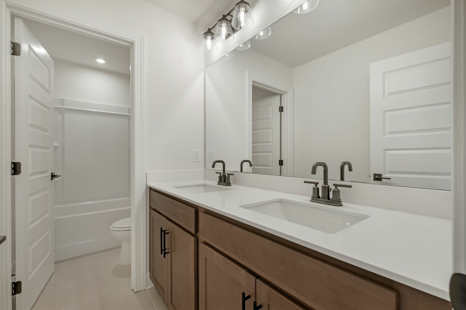 secondary bathroom with wood cabinets, white countertops, and a shower and tub combination