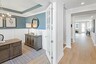 study with wood flooring, large desk and chair, judges paneling on the walls, and a tray ceiling
