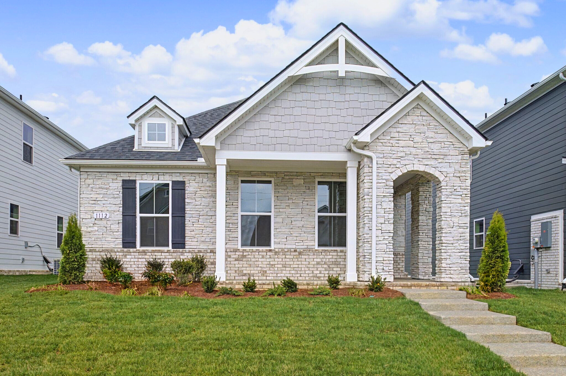 exterior with brick, stone, and covered front porch