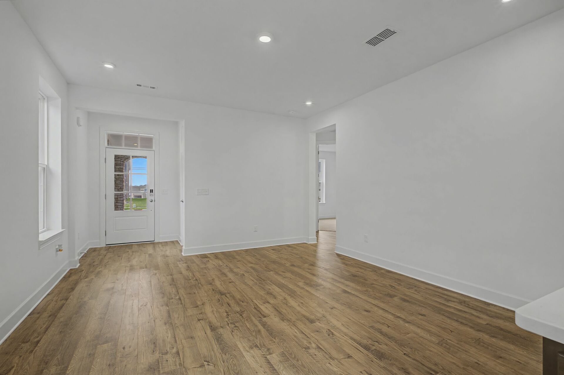 great room with wood flooring, view of the entry way, and large windows
