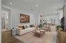 great room with wooden floors, large windows, an area rug, couch, wall art, wooden coffee table, and wooden tv stand