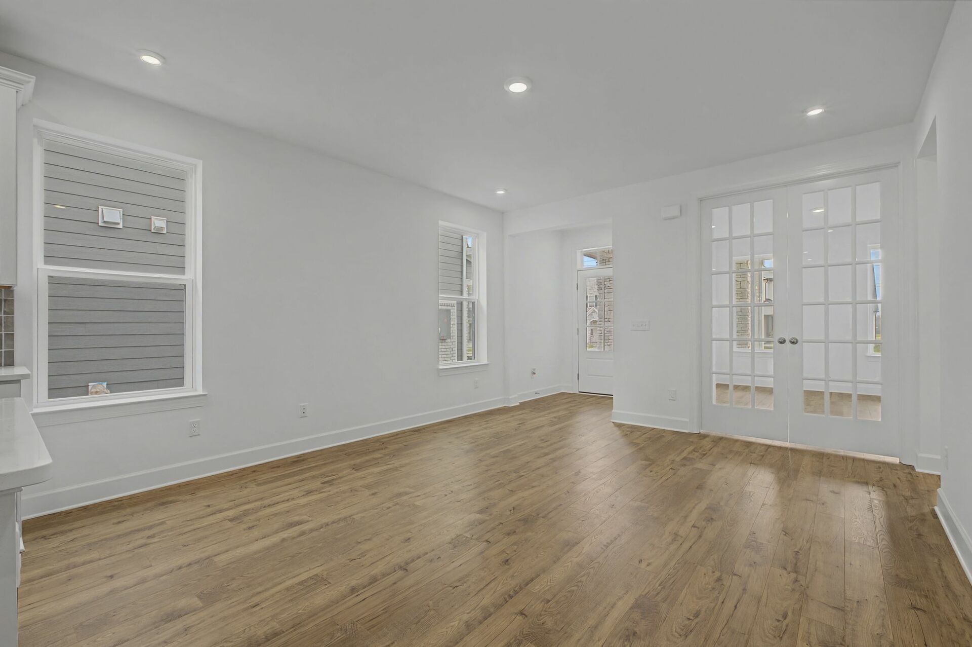 great room with wood flooring, large windows, and french doors into the study