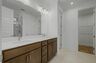 primary bathroom with double sink vanity, wood cabinets, and white countertops
