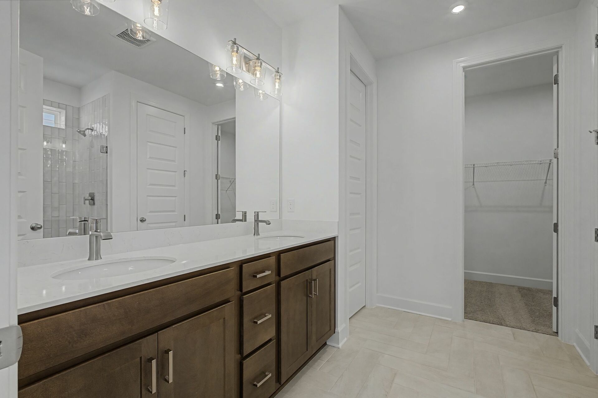 primary bathroom with double sink vanity, wood cabinets, and white countertops