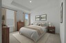 bedroom with carpet, large windows, a wooden dresser, wooden nightstand, and wall art