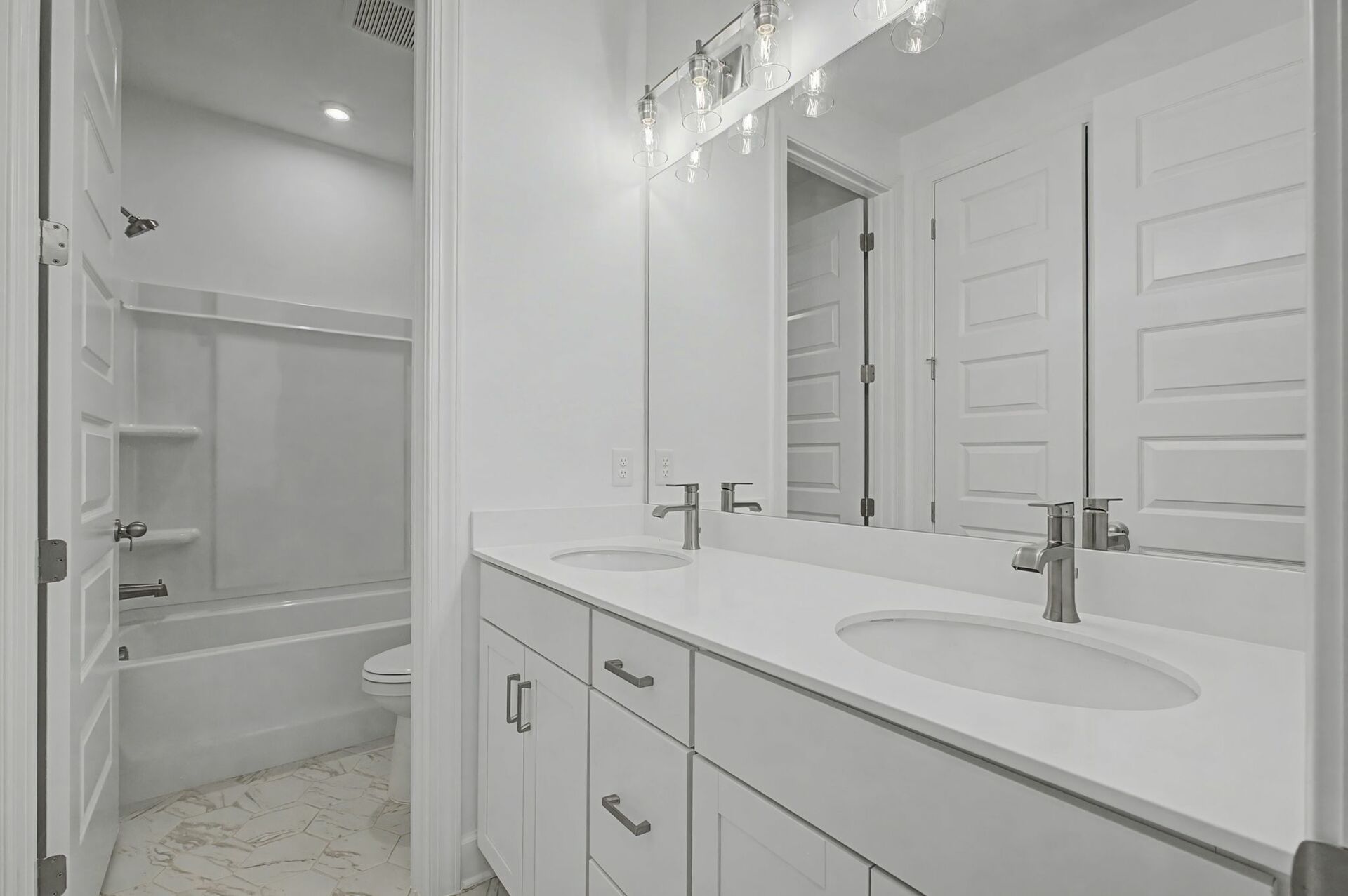secondary bathroom with double sink vanity, white cabinets, and a shower and tub combination