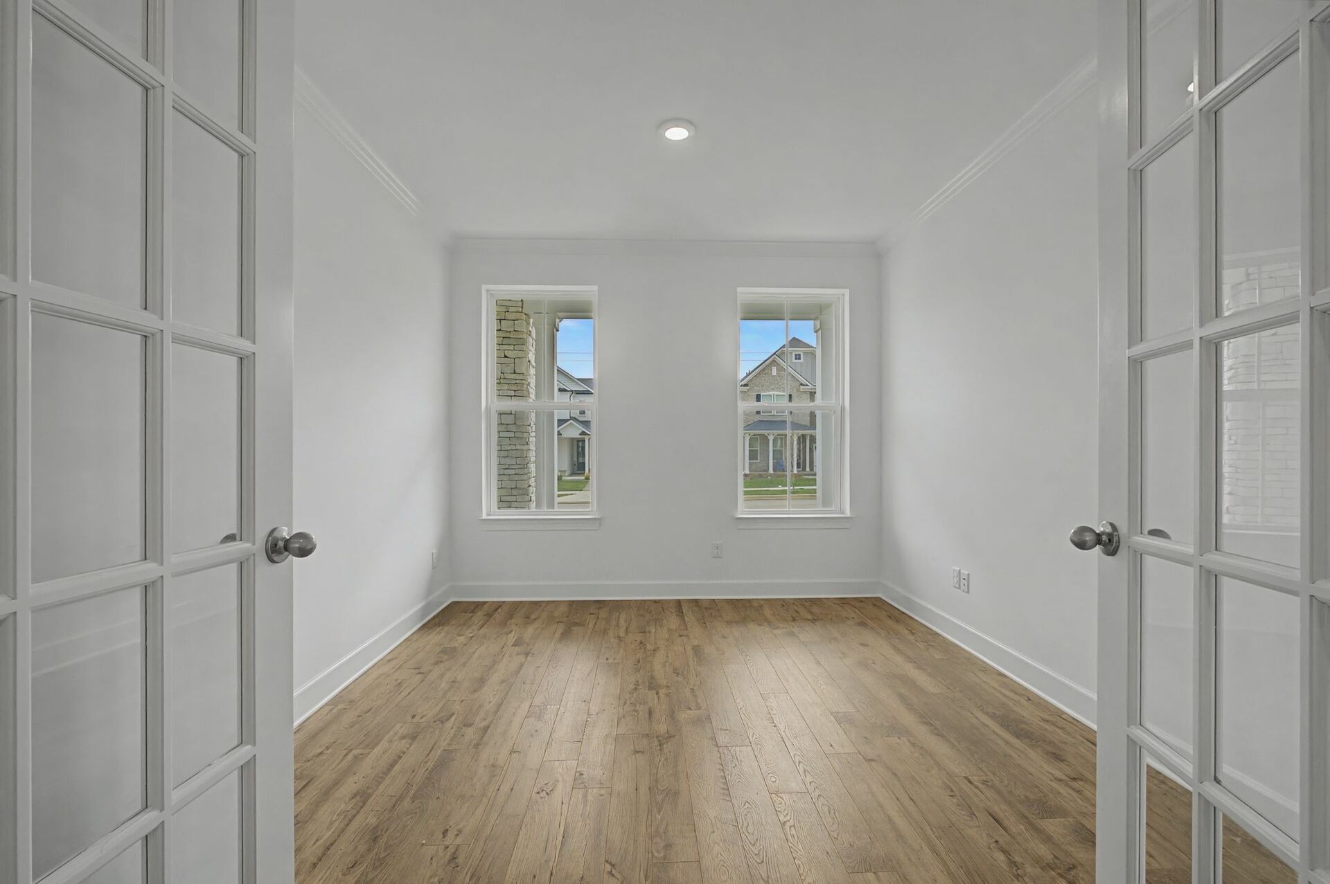 study with wood flooring and glass french doors