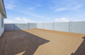 spacious dirt backyard with a concrete block wall