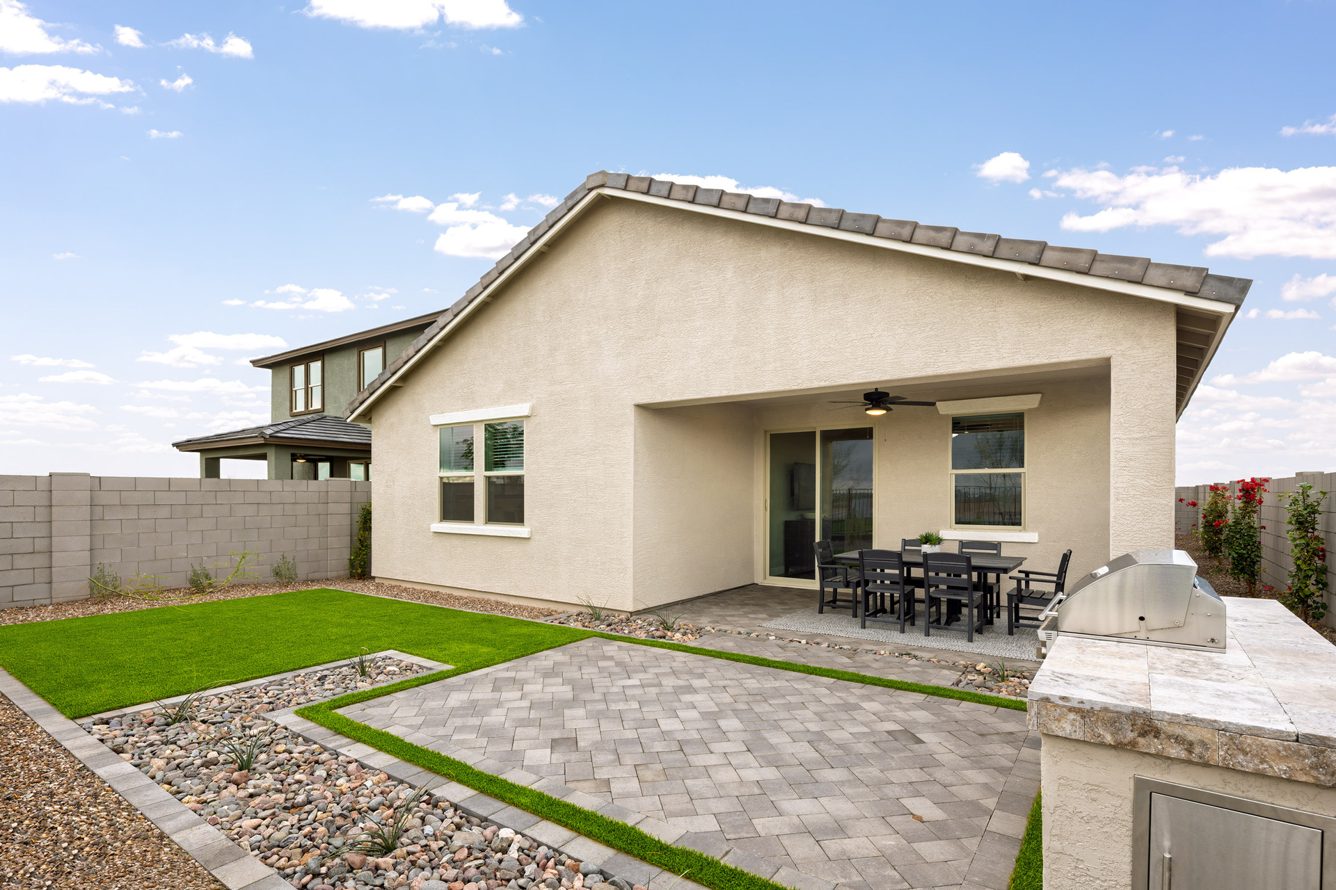 spacious backyard with pavers, artificial grass, and outdoor grill