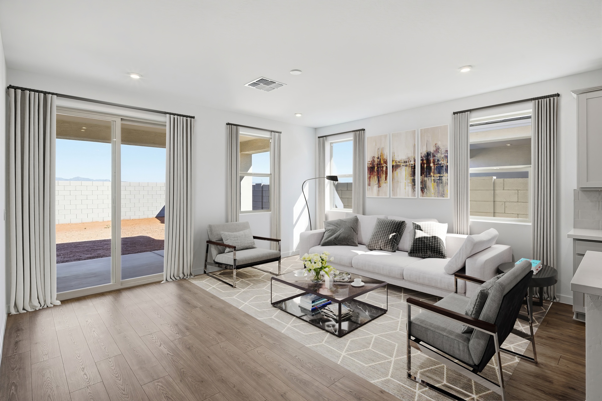 open-concept space with a large white couch, black coffee table, and dark grey accent chairs