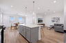 open-concept with views of the great room with a large grey L-shaped couch, and walnut furniture