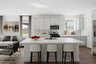 kitchen with quartz countertops. stainless-steel appliances, and white barstools