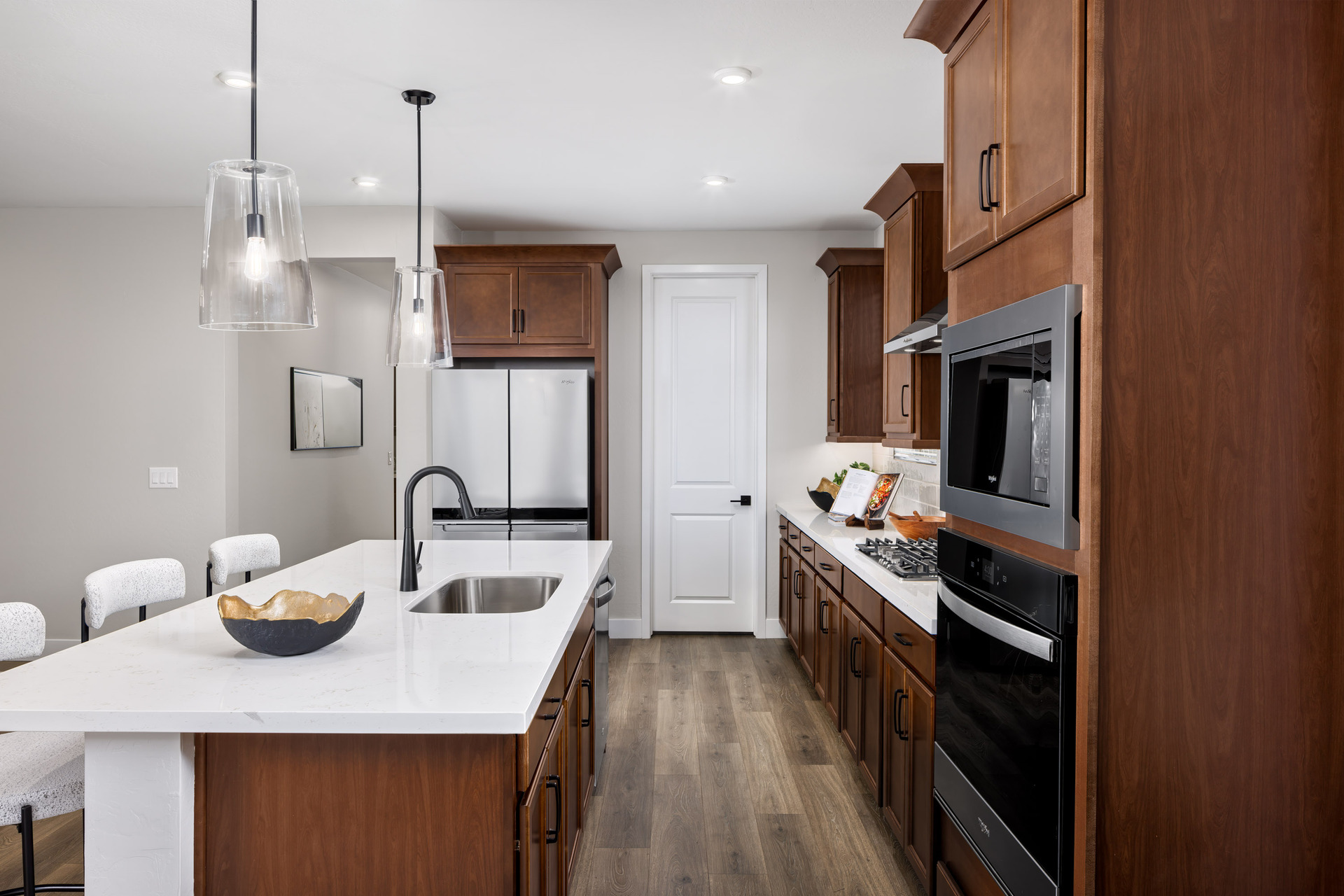 kitchen with brown cabinets, quartz countertops, and white barstools