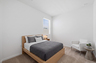 bedroom with oak bedframe, full-sized bed, and white accent chair