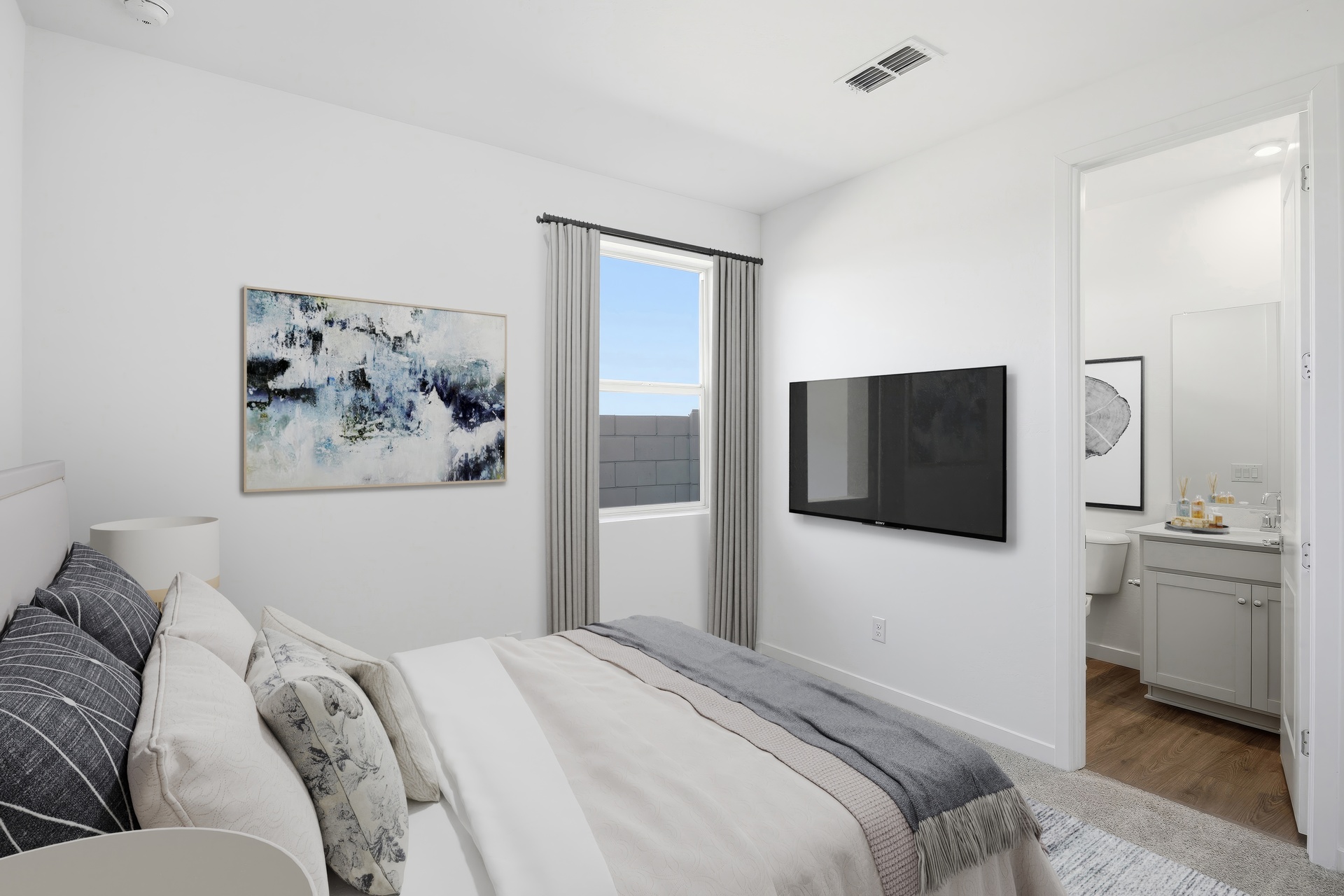 bedroom with a large bed with a white duvet cover, a white rug, and a mounted tv