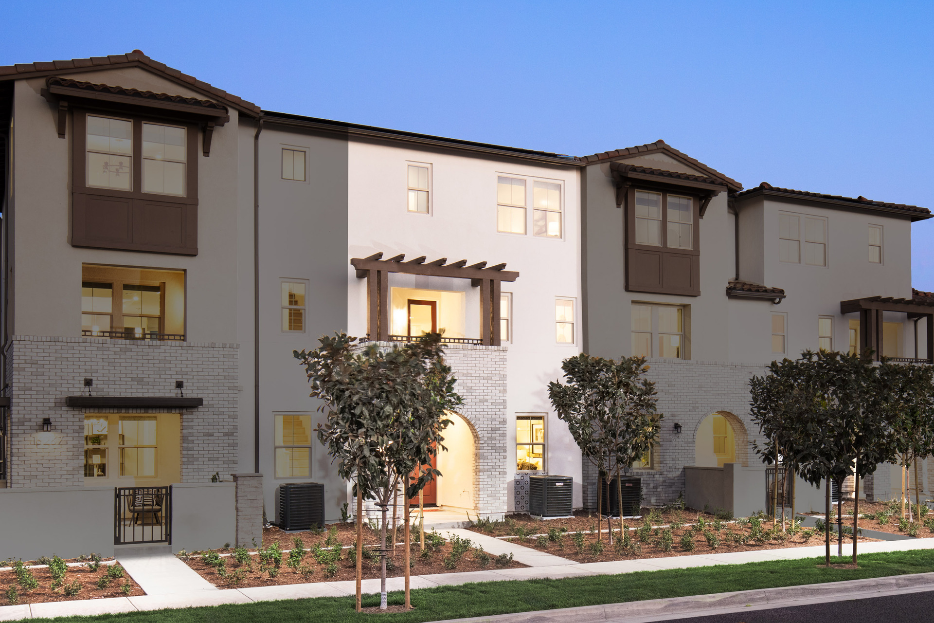exterior of three-story townhome with arched covered porch and neutral paint