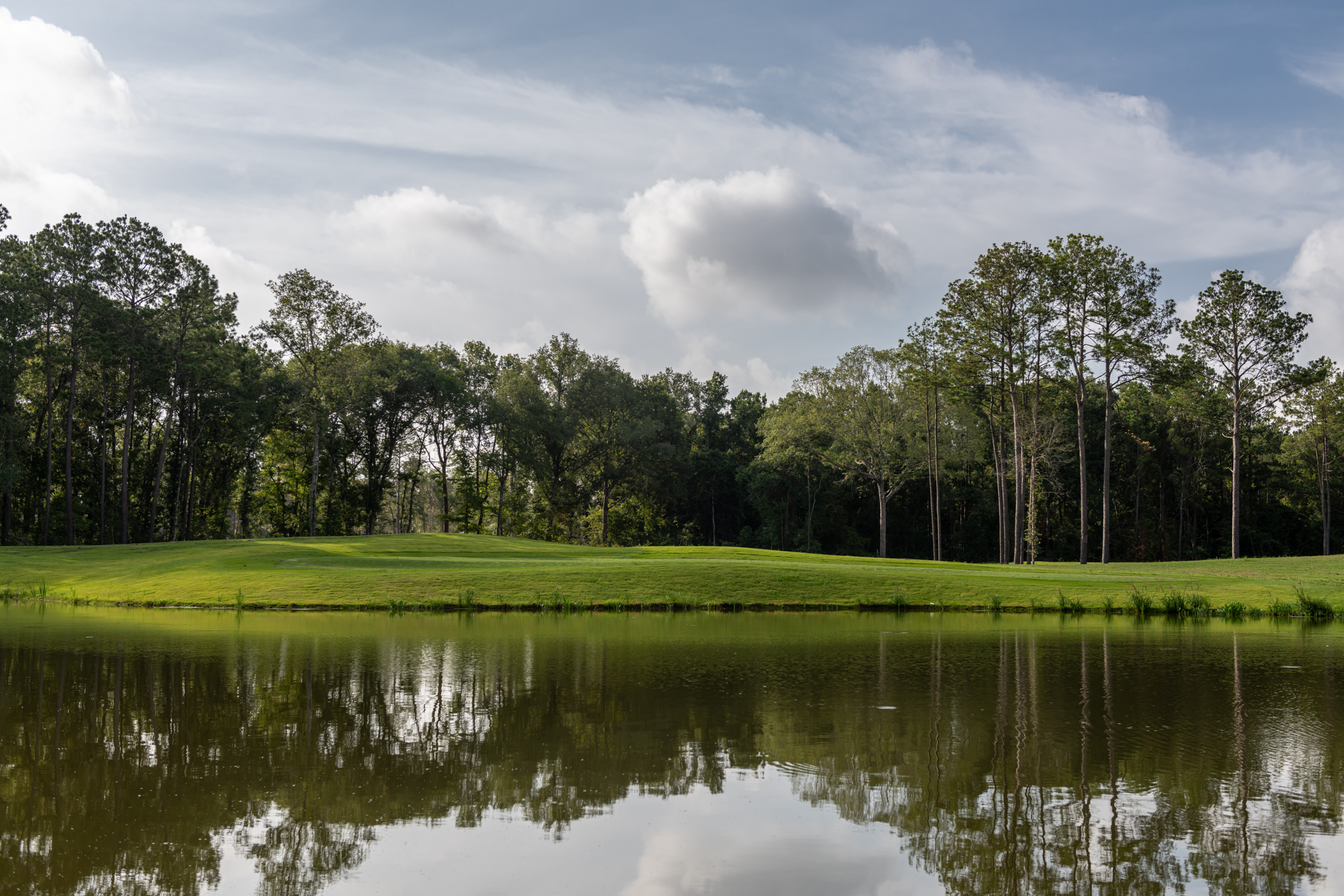 golf course next to water and wooded area