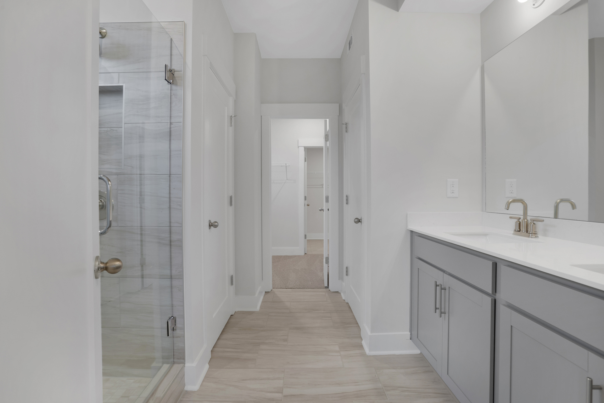 primary bathroom with gray cabinets and walk-in shower