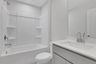 secondary bathroom with gray cabinets and shower/tub combo