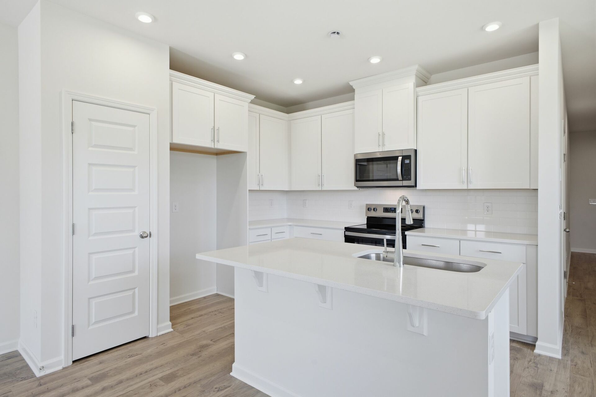 kitchen with white cabinets and counters, wood floors, and stainless steel appliances